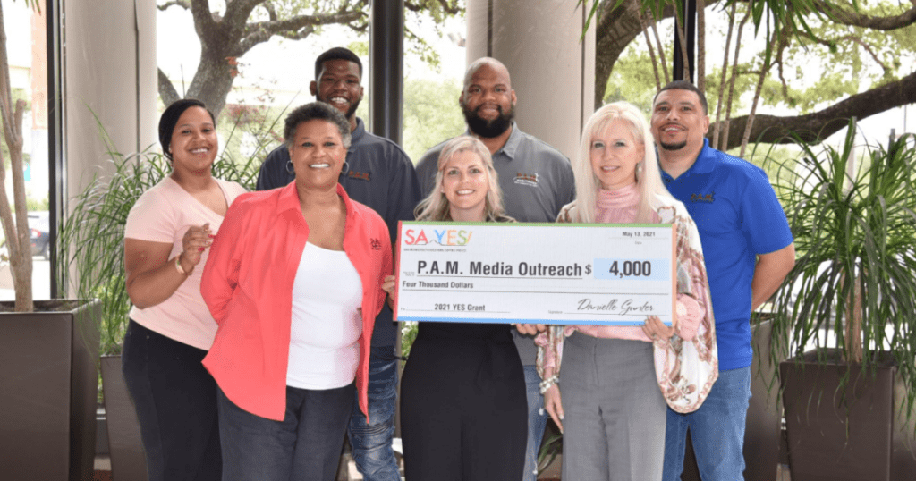 An image of SA YES presenting a large check to PAM Media Outreach as part of their SA YES grant program with PAM Media Outreach and SA YES staff and board members present