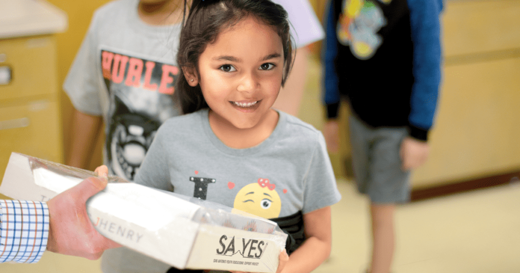 Image of an elementary student receiving a box of SA YES supplies